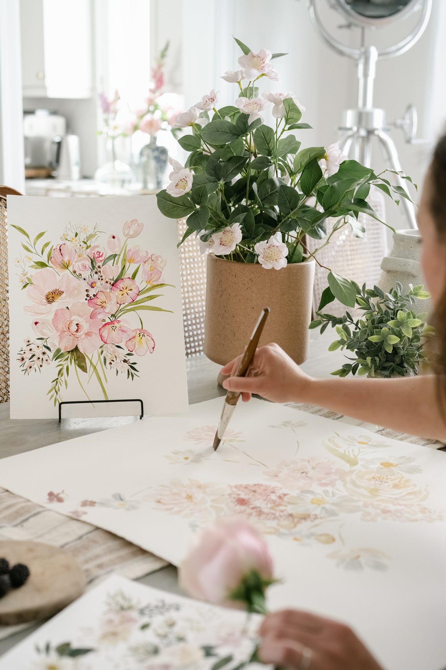 Artist painting flowers in studio with watercolour paints, Pink tulips art print in background